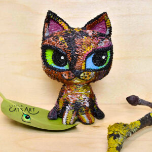 Tortoiseshell cat sculpture with big green-blue eyes