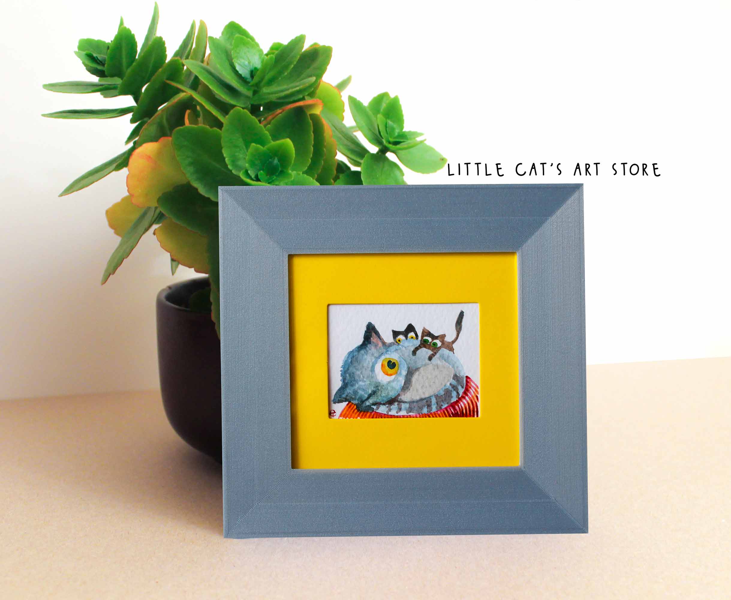 Watercolour painting depicts three cat family members next to a plant