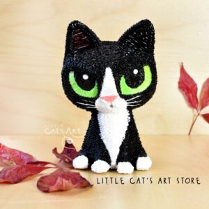 Tuxedo cat figurine with black and white coat and green eyes