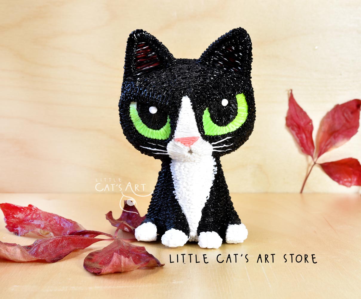 Tuxedo cat figurine with black and white coat and green eyes