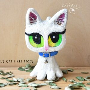 White cat figurine with green-yellow eyes and mini blue collar