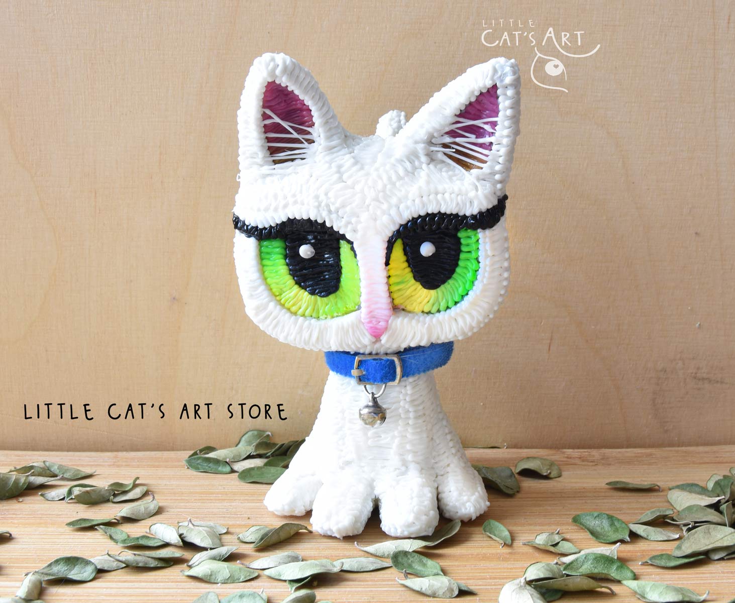 White cat figurine with green-yellow eyes and mini blue collar