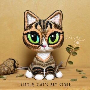 Tabby and white cat figurine with green eyes