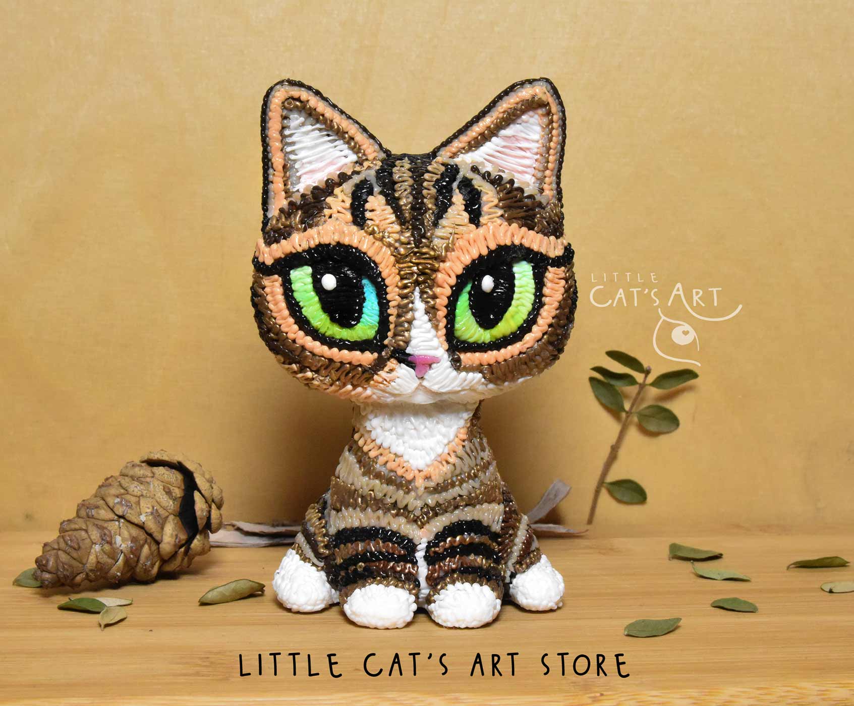 Tabby and white cat figurine with green eyes