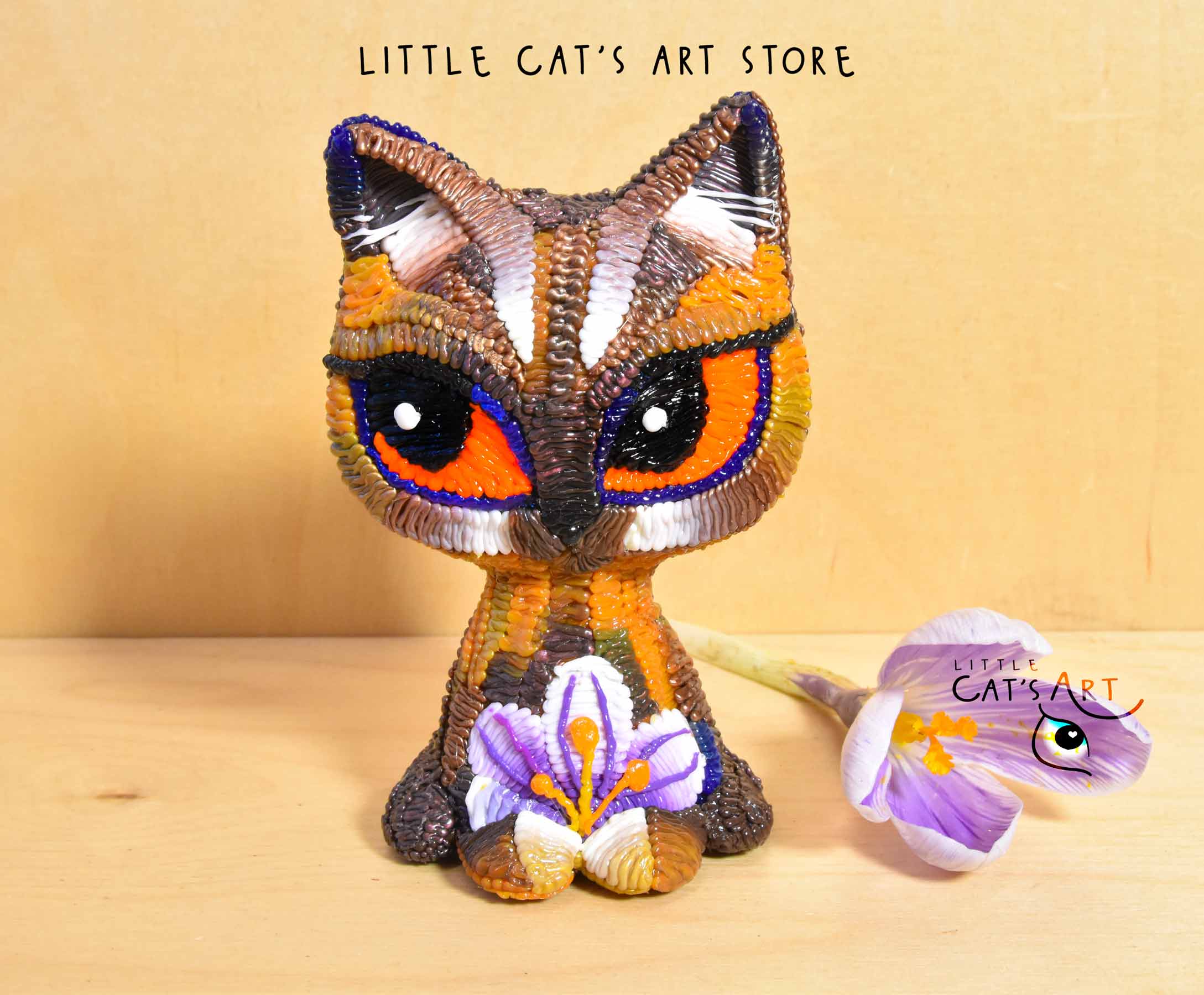 Chocolate cat figurine with orange eyes and white-purple crocus decoration