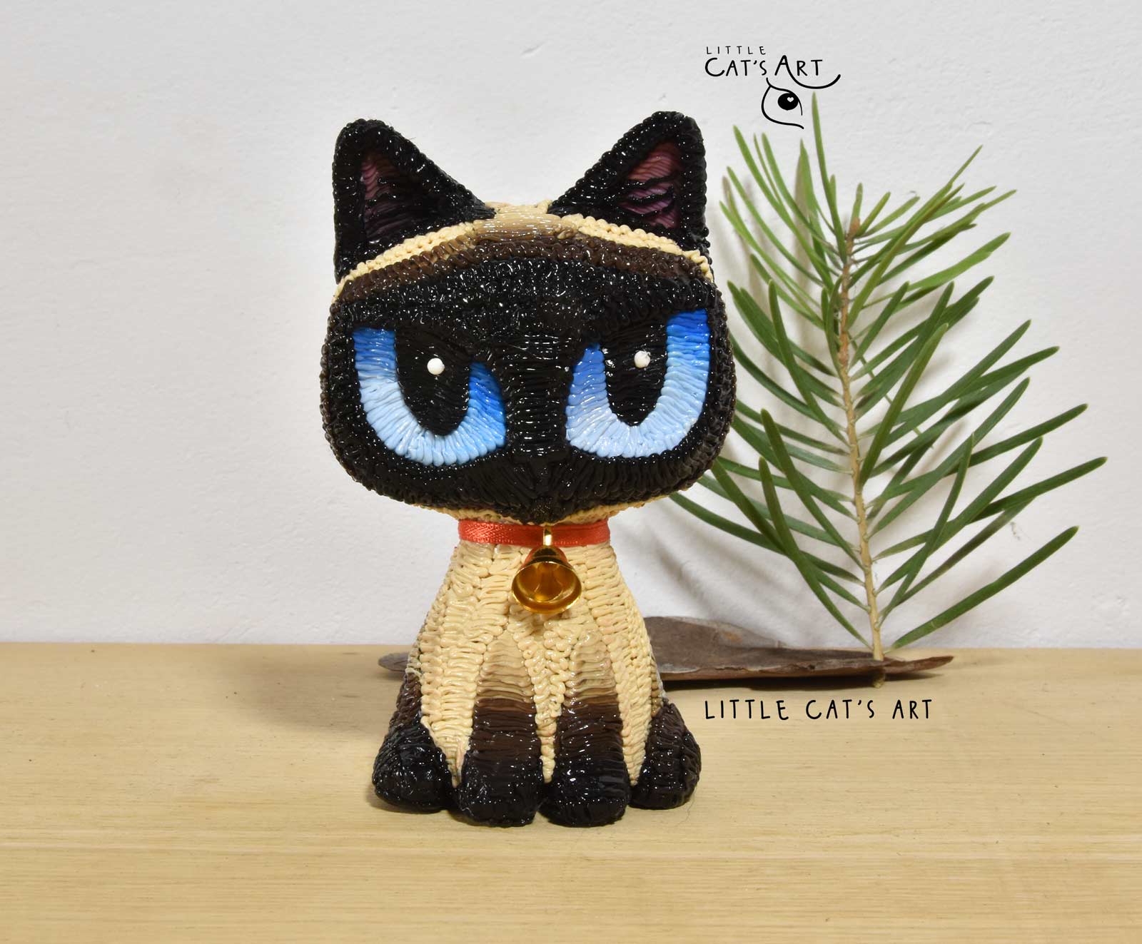 Siamese cat figurine with big blue eyes and red necklace