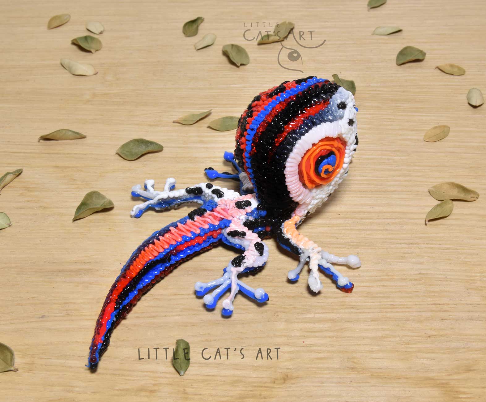 Split-faced black, red, white gecko figurine with orange eye