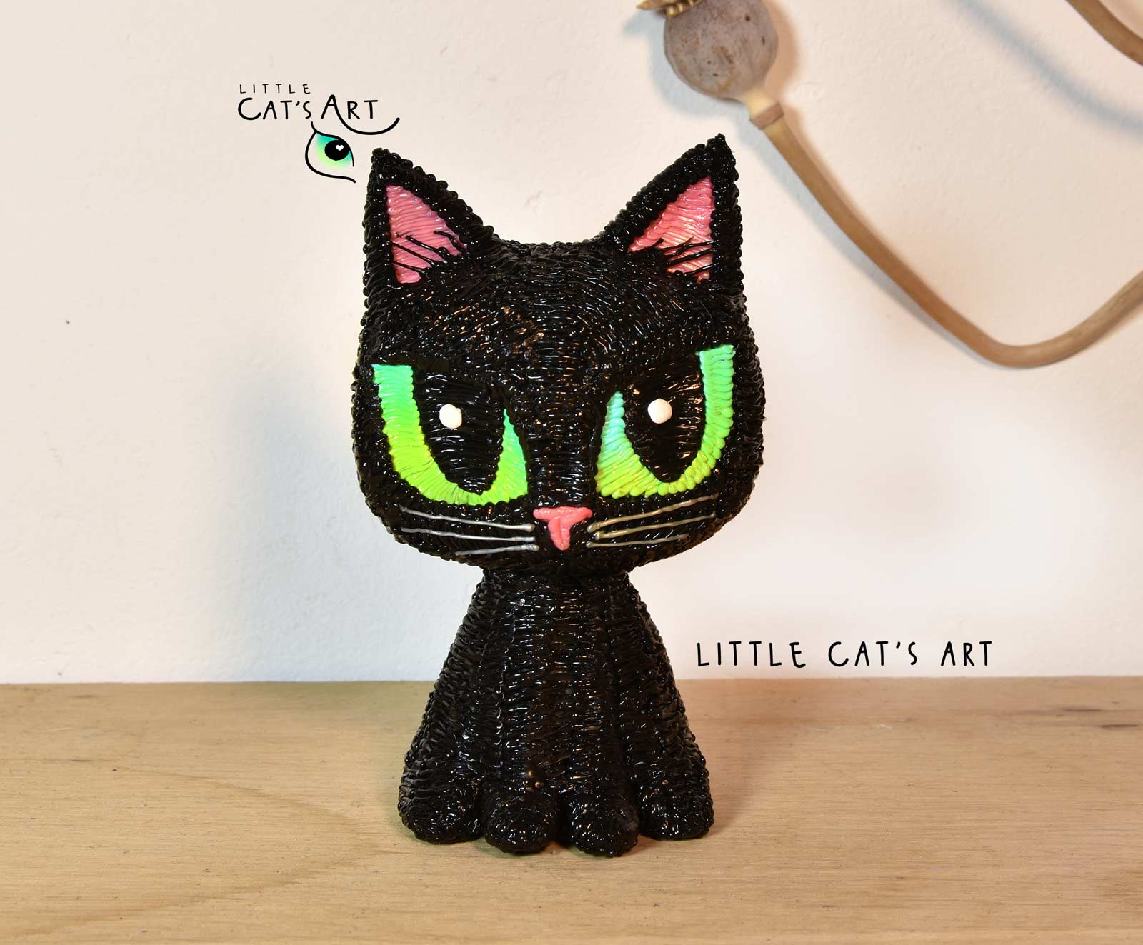 black cat figurine with green eyes and pink nose